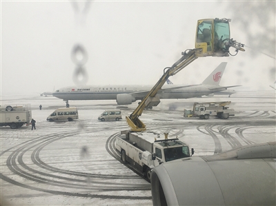 昨日，首都机场航班大面积延误，工作人员正在停机坪除雪。新京报首席记者 陈杰 摄