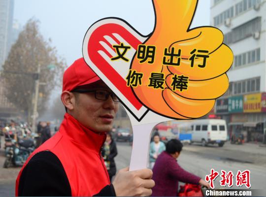 图为志愿者手举"点赞牌在街头为文明出行的市民点赞. 李雅静 摄