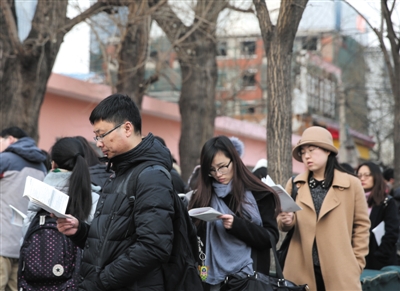 昨日，2016年北京公务员考试呼家楼中学考点。开考前，考生在考场外阅读材料。新京报记者 卢淑婵 摄