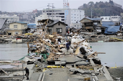 2011年3月15日，日本宫城县石卷市，海啸退去后，一座桥梁上堆满房屋残骸。