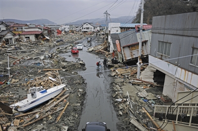 2011年3月15日，日本石卷市街头，海啸摧毁了房屋，也把渔船冲到街头。