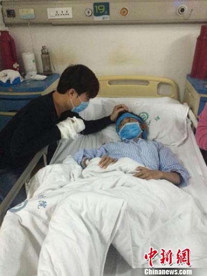 李鹏举在医院照顾弟弟，一边抚摸着弟弟的头，一边逗弟弟开心。 李婉君 摄