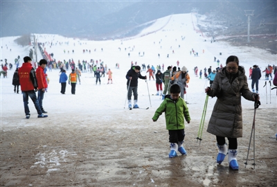 昨日，八达岭滑雪场，一对母子正走向游客中心，由于地面湿滑，母亲提醒孩子要小心。A06-A07版摄影/新京报记者 卢淑婵 薛珺 王佳慧 信娜