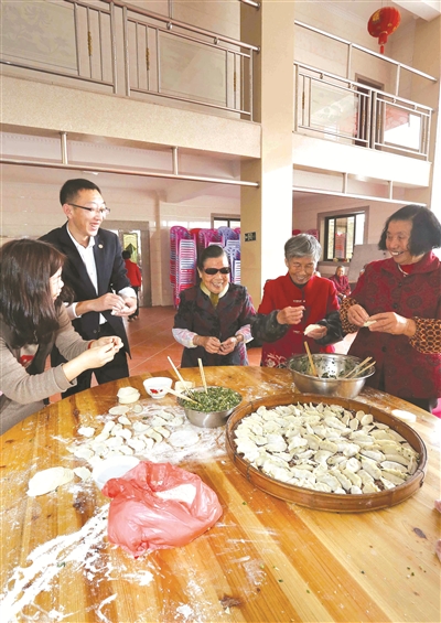 志愿者陪老人包饺子。