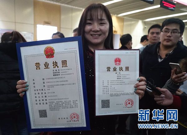 这是2015年3月26日,江西国道贵金属贸易有限公司法定代表人李霞在展示她领到的南昌全市首张“三证合一”营业执照和副本。2015年10月1日起,“三证合一、一照一码”的企业登记模式在全国全面推行。新华社记者 陈子夏