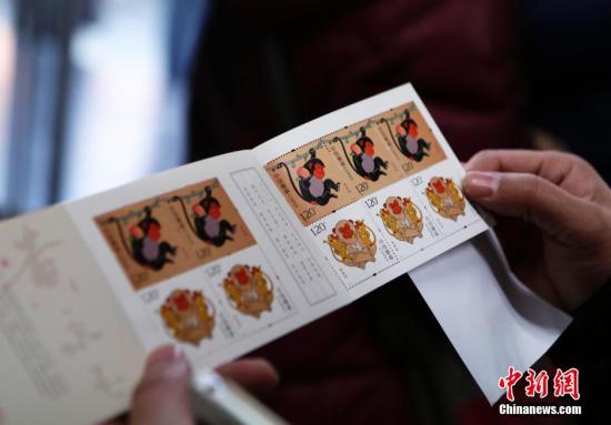 资料图:1月5日,北京市民展示刚刚购买的猴票。当日,中国第四轮猴年生肖邮票《丙申年》正式发售。该邮票1套2枚,面值为2.40元人民币。图案内容分别为:灵猴献瑞、福寿双至。 中新社记者 李慧思 摄