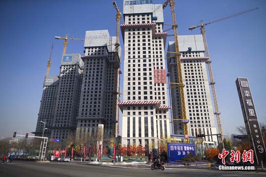 材料图:1月19日,大众从一在建贸易楼盘前通过。中新社记者 张云 摄