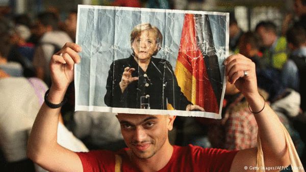 难民举着有默克尔肖像的海报 来源：法新社