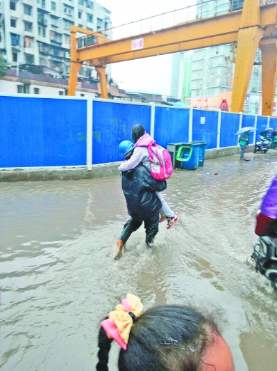 小学门前积水 3名地铁工人背百余学生趟水入校