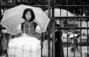 昨天上午10點半,留宿生們將被子等物件搬回家。一位門生冒雨在校門口期待家長來接。資訊時報記者 陳引 練習生 何家貴 攝