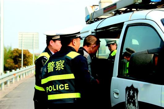 楚天金报讯 图为:犯罪嫌疑人被押上警车