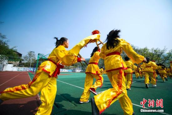 资料图：重庆市澄江小学的百余名学生，在操场上拿着一米长的小板凳舞起“板凳龙”，共迎春暖。陈远鸿 摄