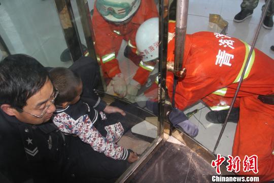 图为救援人员正在对卡住男童右腿的门缝进行扩张