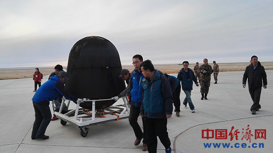 直升机飞走后,工作人员将实践十号卫星返回舱运送至载荷交接现场.