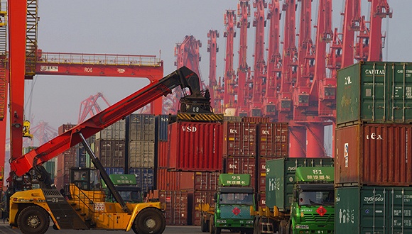 山东日照港集装箱码头一片繁忙，场内机械在装卸集装箱货物。图片来源：视觉中国
