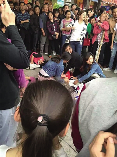 人和125路公交车站左近,4名女孩在对老太施救。 网友图
