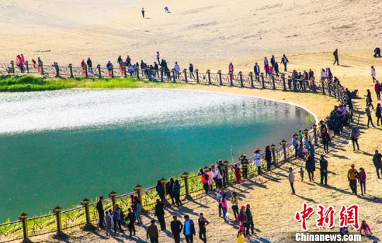 5月1日，甘肃著名景点月牙泉，出现了罕见的铁背鱼浮出水面的景象。图为大批游客簇拥着月牙泉抓拍“铁背鱼”。 王斌银 摄