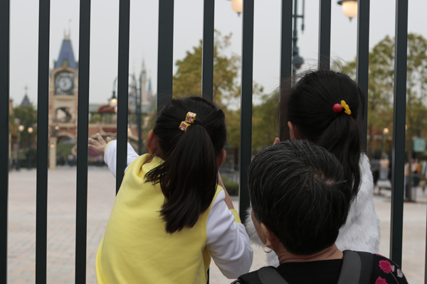 2016年5月7日，无法入园的游客透过栏杆观看迪士尼城堡。 澎湃新闻记者 朱伟辉 图