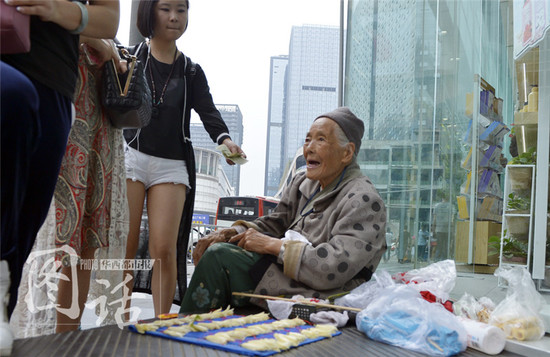 一位佝偻着身子的婆婆，坐在成都盐市口附近一商店门前的石阶上，面前是她的“摊位”。从婆婆随身佩戴的胸牌得知，她名叫罗锦凤，今年94岁。在这里卖黄桷兰已经10年了，周围人都叫她“黄桷兰婆婆”。