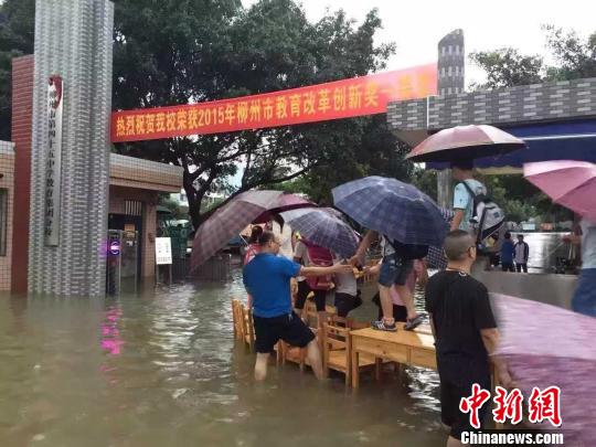 图为柳州市第四十五中学用课桌搭路,让孩子通行。 钟欣 摄
