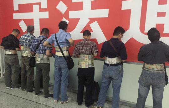 被查处的腰间绑着涉嫌走私手机的男子。文内图均来自中新网