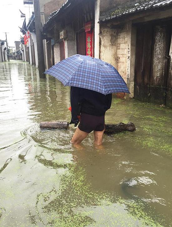孔城老街居民马世方趟过积水。