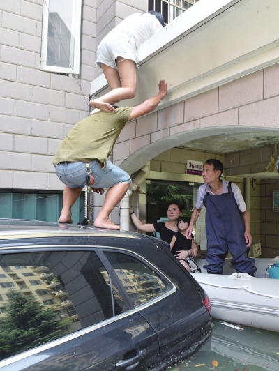 7月9日,由于楼道被淹,南湖一小区被困居民只能从二楼搭人梯转移。