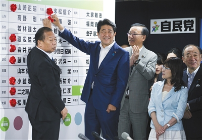 7月10日晚,日本东京,日本首相安倍晋三来到位于自民党总部的开票中心,为展板上写着的每个当选者的名字贴花。 图/视觉中国