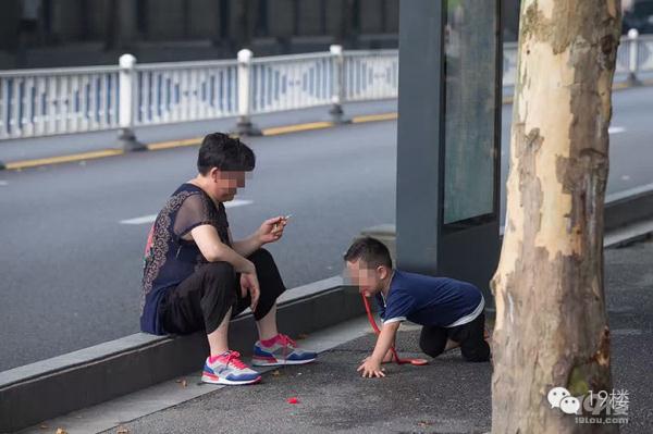 大妈坐马路边 边抽烟边让孙子学狗爬(图)