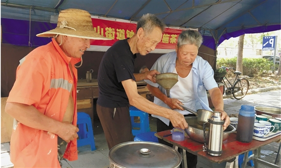 余阿王老人（中）正在为环卫工灌茶水。 钱江晚报 图