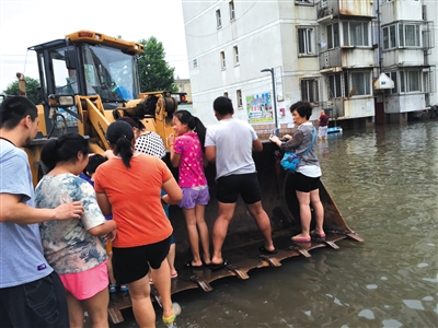 昨日,大兴隆盛园小区,进出小区的道路被淹没,居民乘铲车回家。新京报记者 王煜 摄