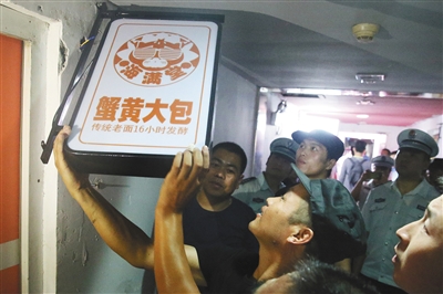 8月8日,北京朝阳区北京像素北区,执法人员正在摘除一家无照经营的饭店招牌。