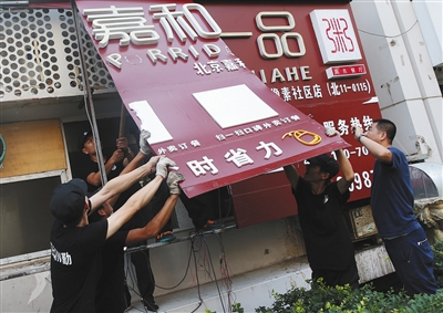 在北京朝阳区北京像素北区,执法人员正拆除一家无照经营饭店的户外广告。