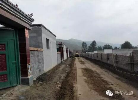山坳里破旧的土坯房和山脚下正在兴建的新村庄形成鲜明对比,诠释出“天壤之别”的含义。