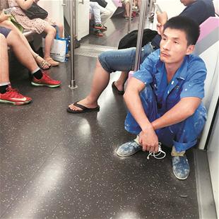 楚天都市报讯 图为:蓝衣小伙蹲在地铁车厢角落里 网友拍摄