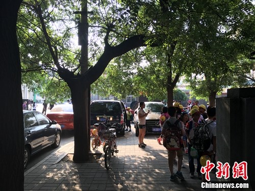 北京某小学门口等待家长接送的学生。汤琪 摄