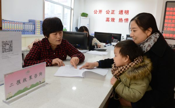 资料图片:工作人员(左)为居民介绍“全面二孩”政策 新华社记者张端摄