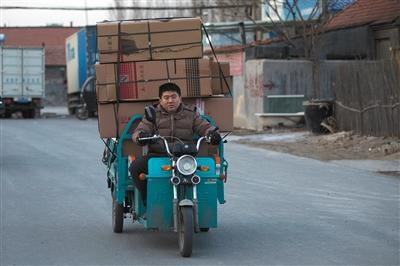 山东滨州淘宝村。30岁的快递员高鑫骑着电动三轮车在送货的路上。