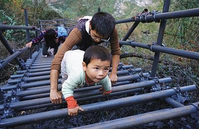 11月19日，勒尔小学的支教老师带着3岁的儿子跟着学生爬钢梯上“悬崖村”家访，过去路不好走，他从来没带儿子上过山。