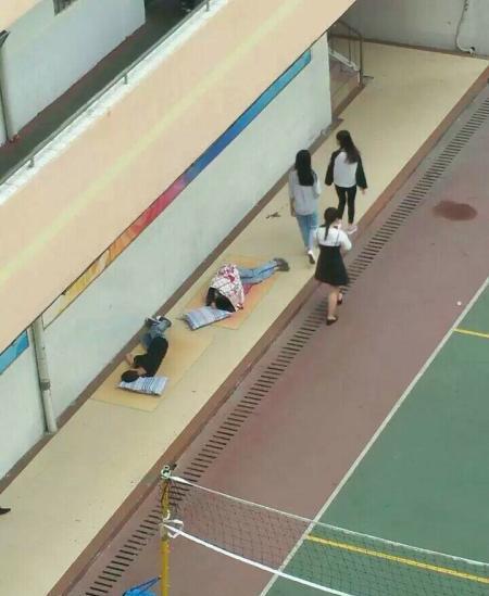 在一处操场旁的走廊上,两名学生睡在草席上。 微博@广西身边事 图
