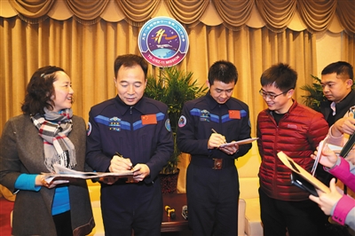 12月7日,航天员景海鹏(左二)、陈冬(左三)在与媒体见面时为记者签名。 新华社记者 琚振华 摄