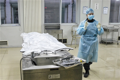 一名女法医在剖解台阁下预备工作。本版拍照/新京报记者 王嘉宁
