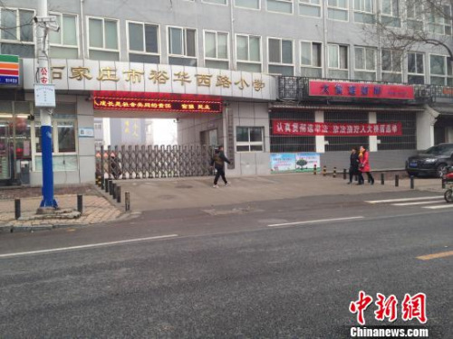 21日下午,一名行人从石家庄市一所小学门前经过。当天,该市小学、幼儿园因重霾停课。 王天译 摄