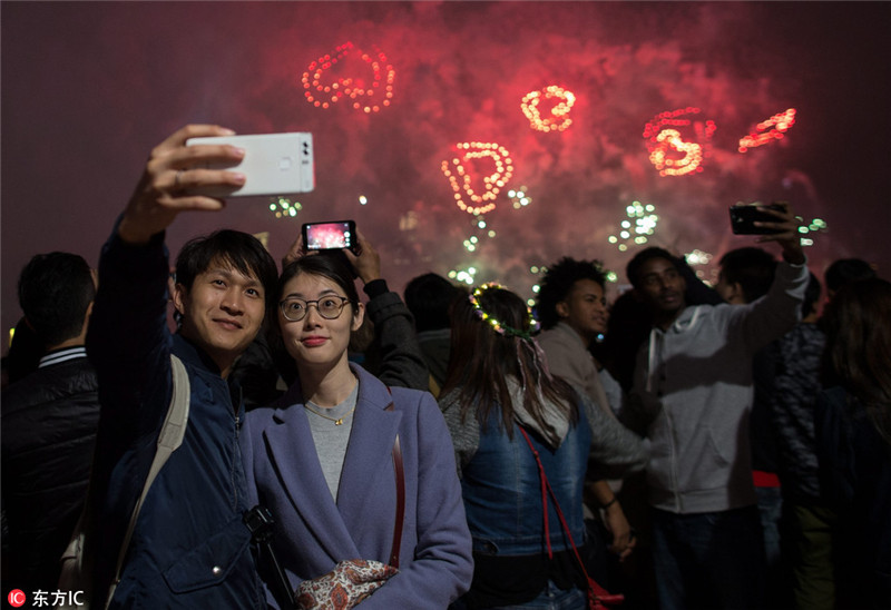 2017年1月1日,中国香港,一年一度跨年烟花汇演在香港维多利亚上空举行,火树银花不夜天,喜迎2017新年到来。 香港会展中心打出2017字样,迎接新年。 一对情侣对着手机,自拍留影。