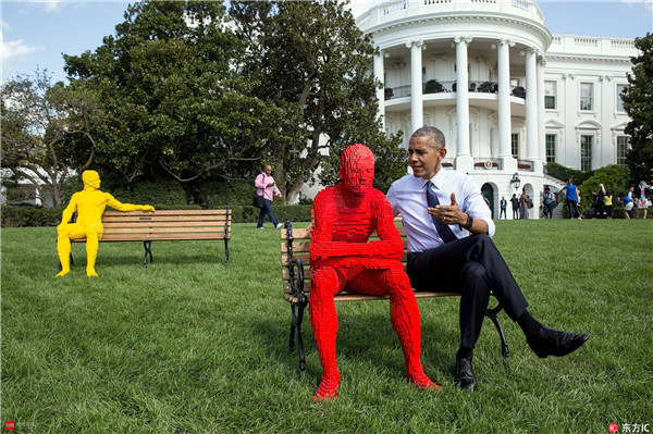 奥巴马坐在艺术家Nathan Sawaya创作的乐高雕塑身旁。