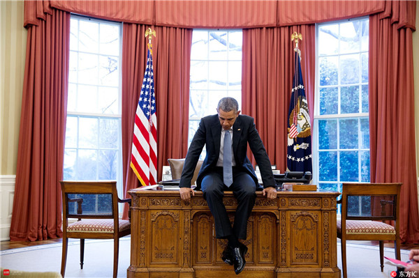 奥巴马坐在白宫办公室的桌上。