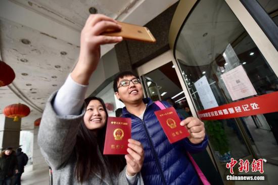 2月14日，北京市朝阳区民政局婚姻登记处前，一对新婚夫妻自拍晒出他们刚领到的结婚证。中新网记者 金硕 摄