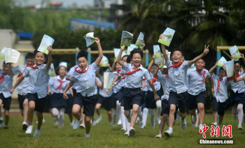 资料图:学生们展示刚刚领到的新学期课本。 孟德龙 摄
