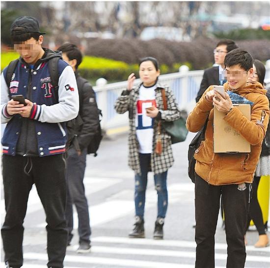 昨天，在杭州市西湖文化广场旁的斑马线前，许多行人低头看手机。