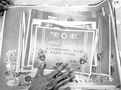 王泽涛手抚女儿蕾蕾历年来获得的奖状